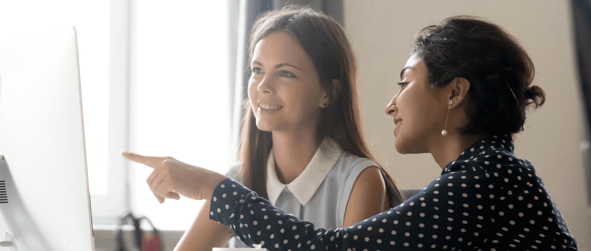 women in office pointing at computer