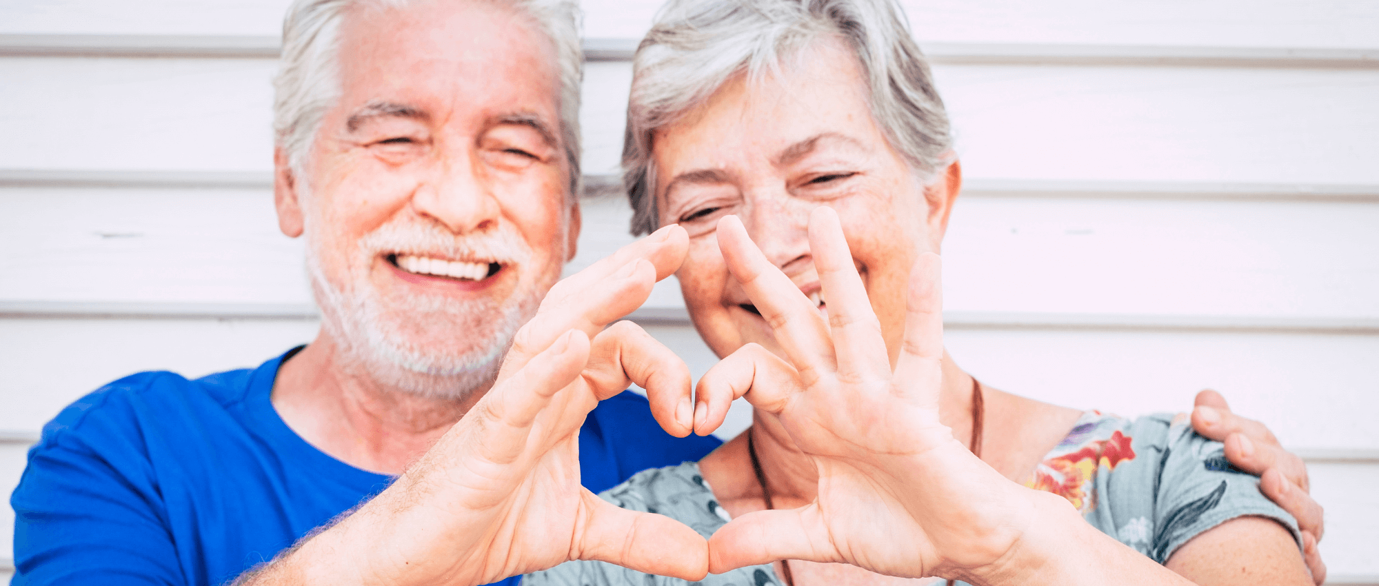 Two senior couple creating a heart shape with their hands