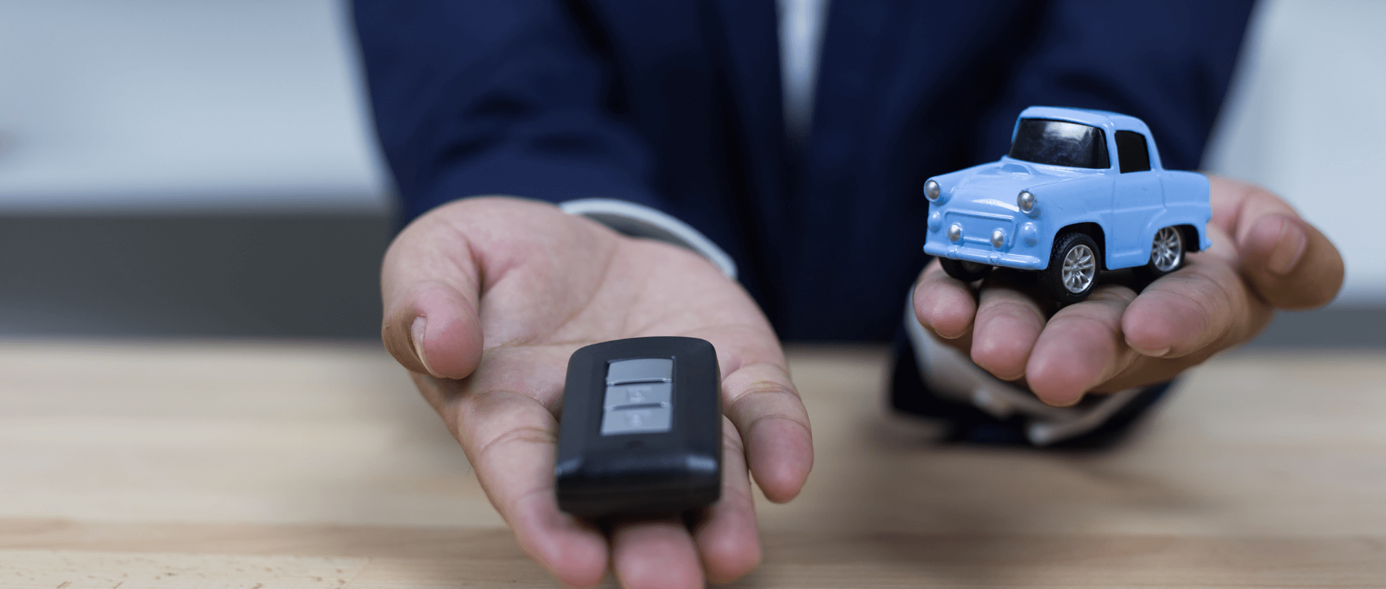 A person holding a toy car and a car key