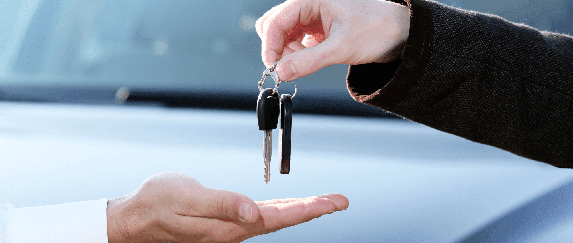 A person giving car keys to another person
