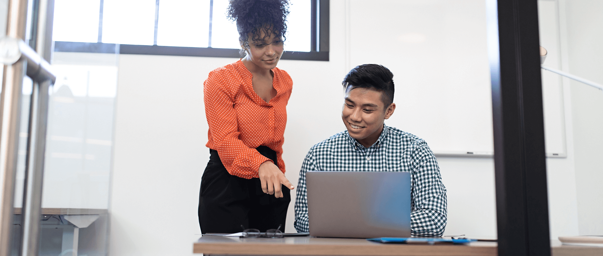 A woman helping out a man on his laptop