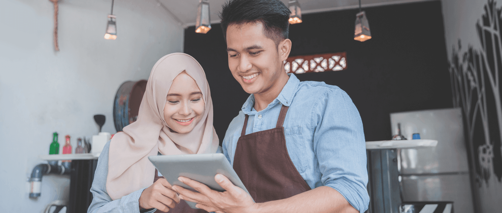 An female owner of a family business coffee shop looking at an I-pad with a man